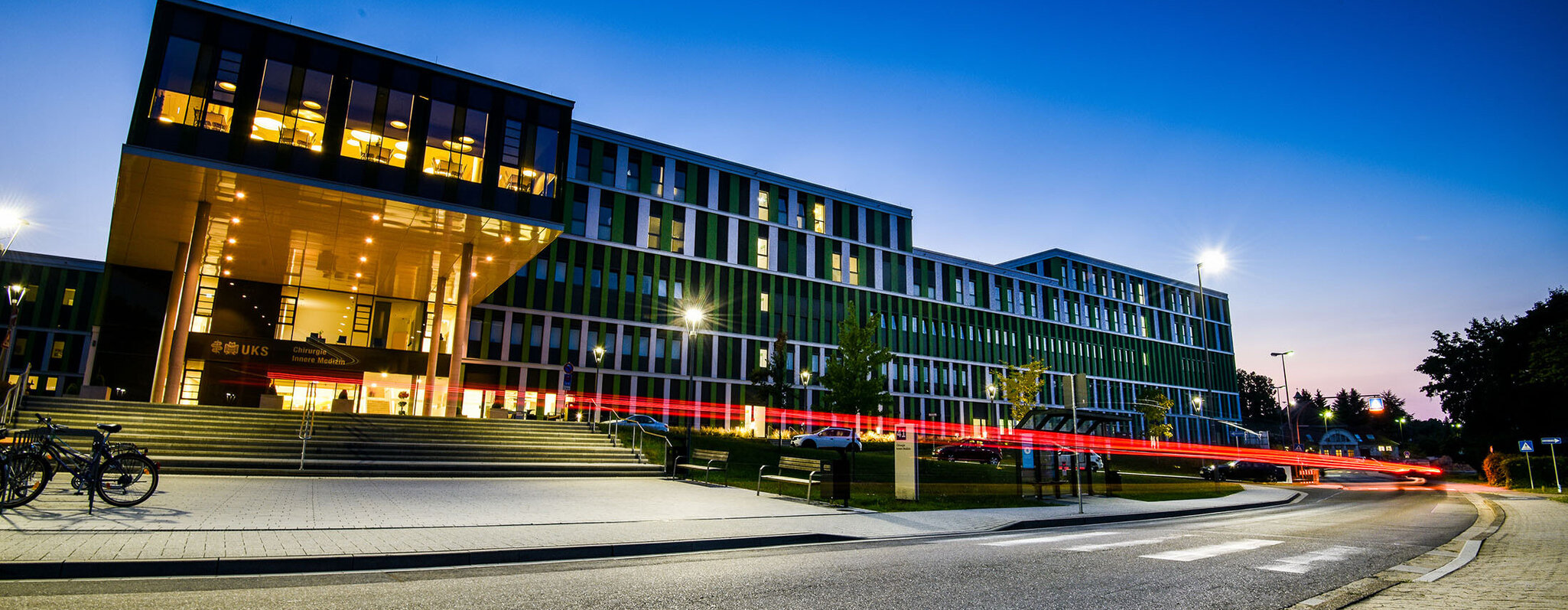 Nächtliche Außenaufnahme der IMED-Fassade mit Haupteingang